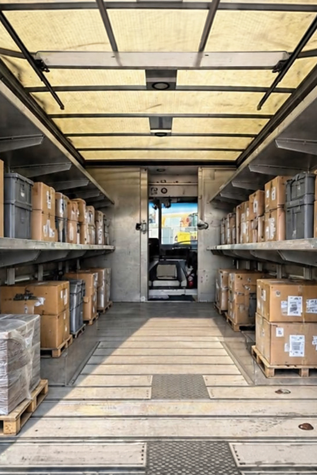 Cargo area with shelving and loaded boxes, looking toward the cab